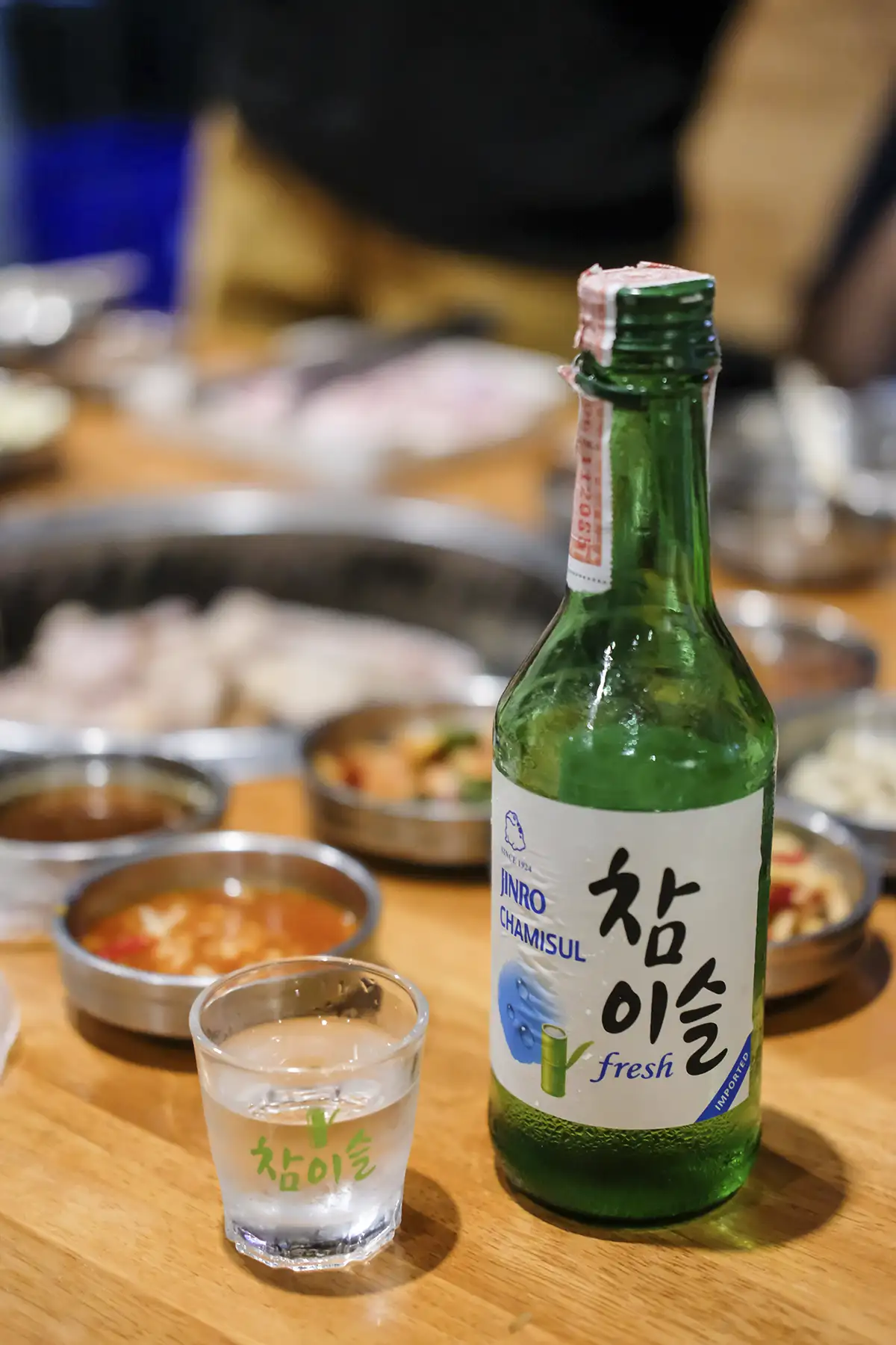 A bottle of Jinro Chamisul soju on a table in a restaurant