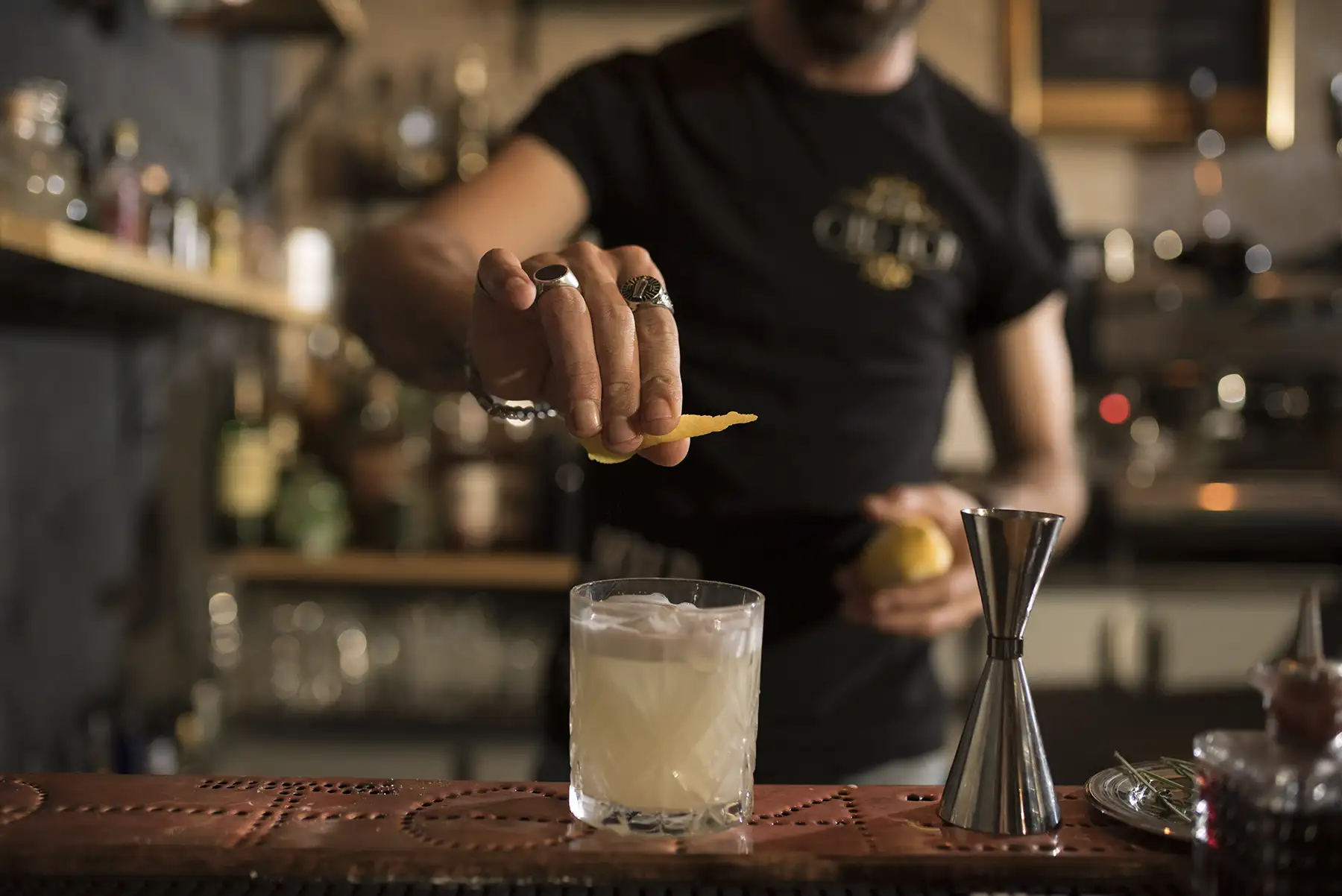 A bartender squeezing a lemon wedge into a mixed drink cocktail