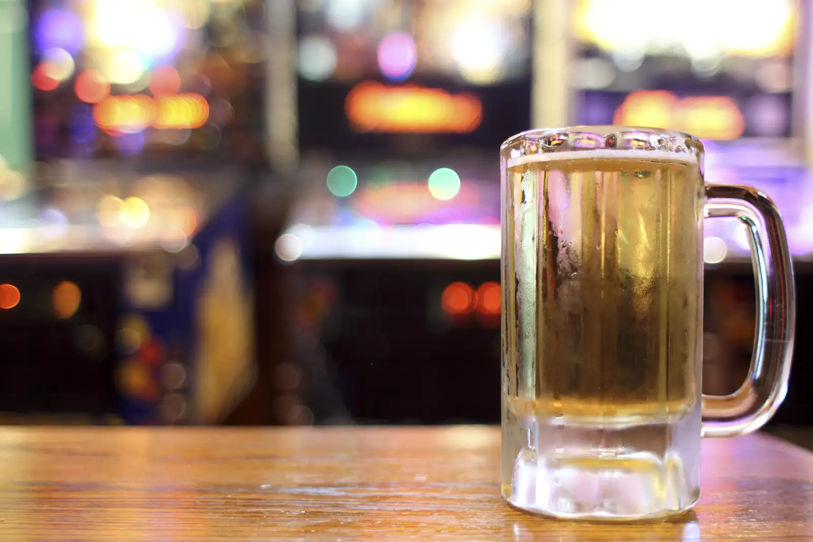 A beer mug with pinball machines in the background