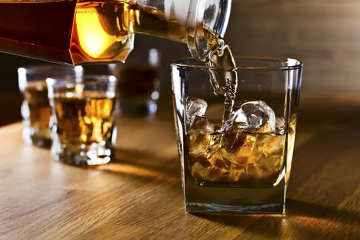 An upclose photo of bourbon or whiskey being poured into a glass