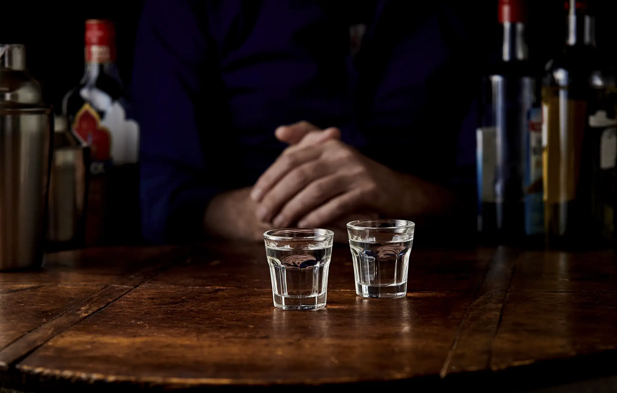 Two small shotglasses of vodka on a bar